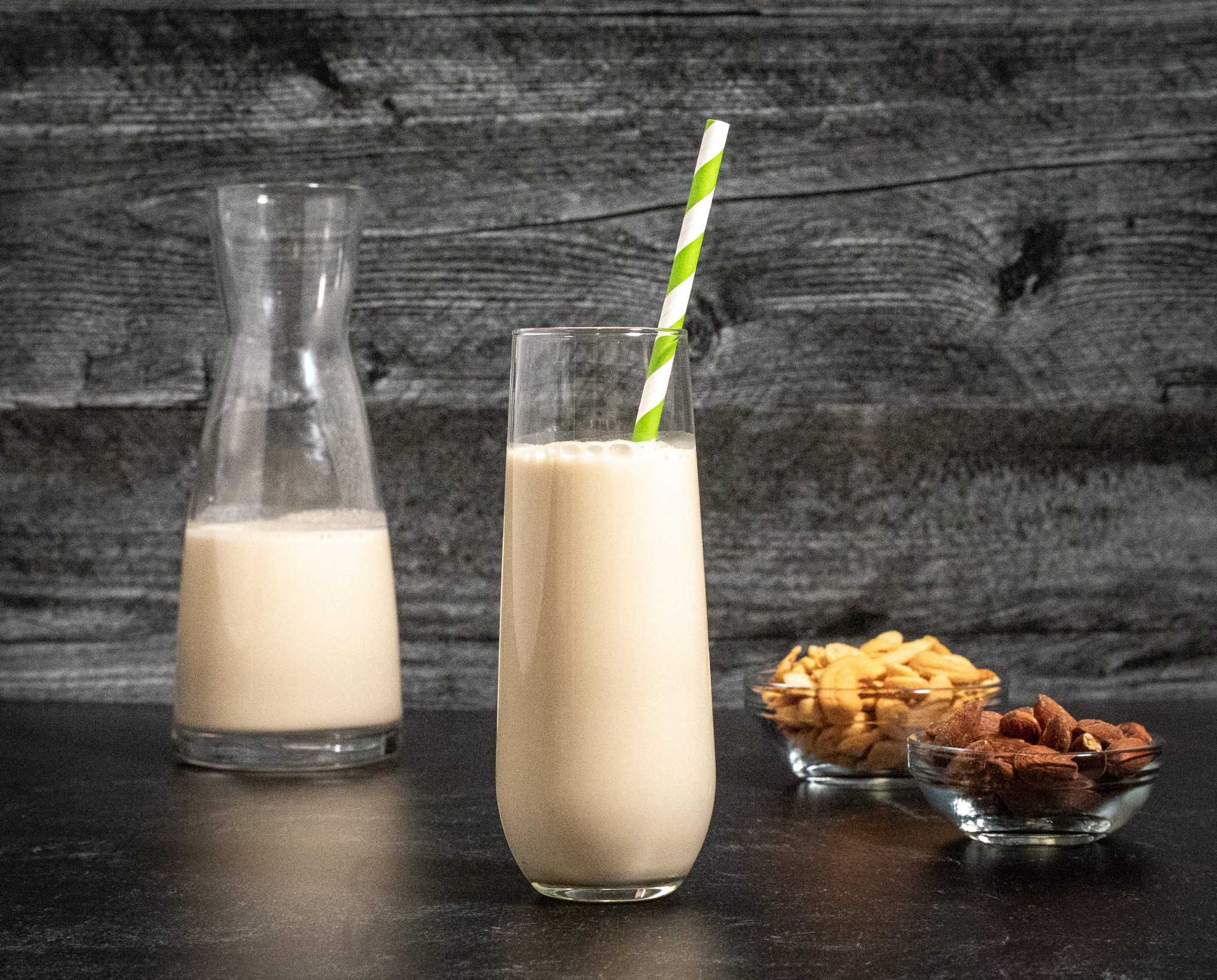 white botanical beverage in glass, nuts in bowl