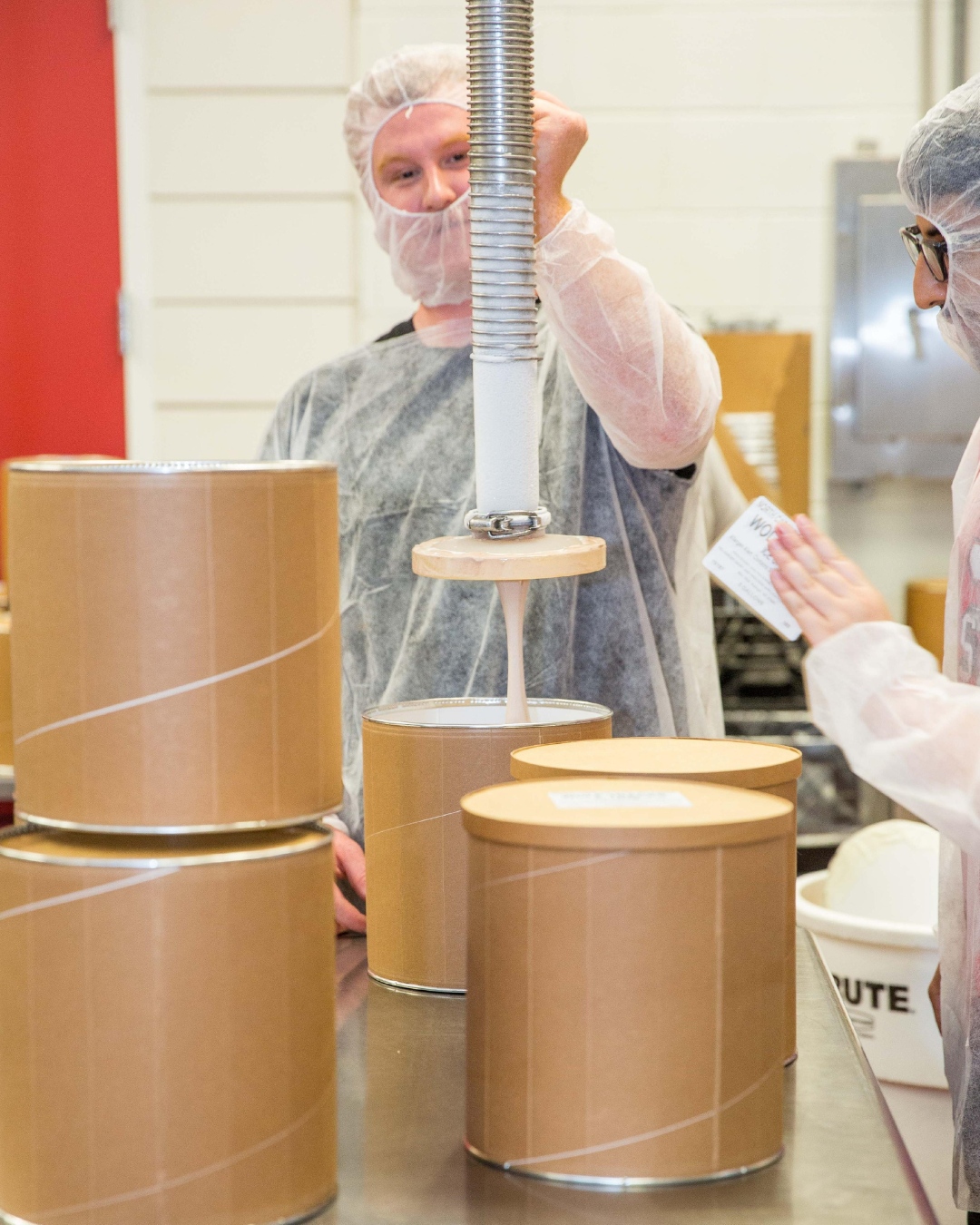 Man in mask and gown filling Howling Cow Ice Cream gallons at NC State