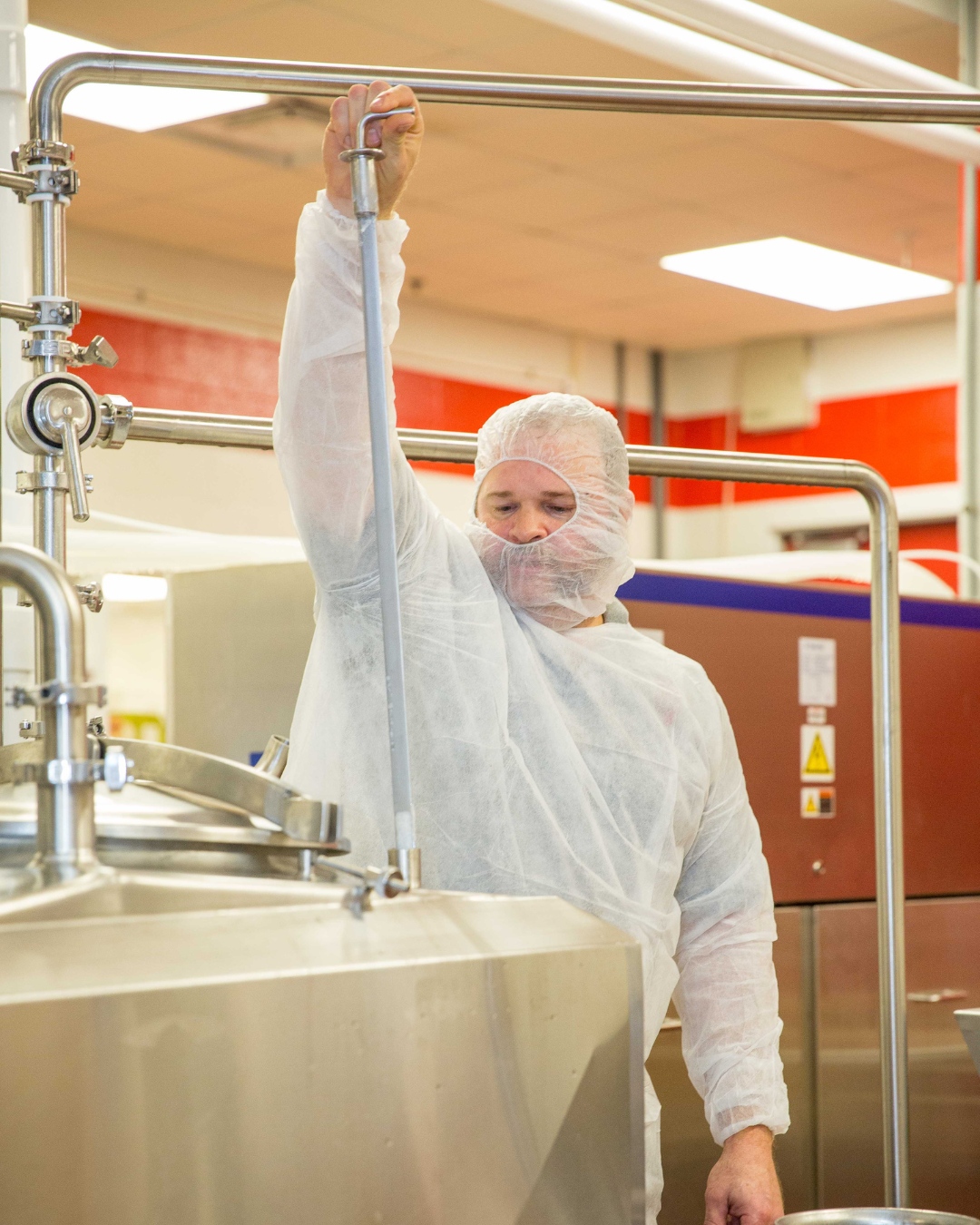 Man in mask and gown processing ice cream in vat at NC State