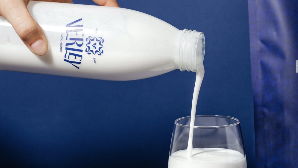 Photo of white bottle of milk being poured into clear glass