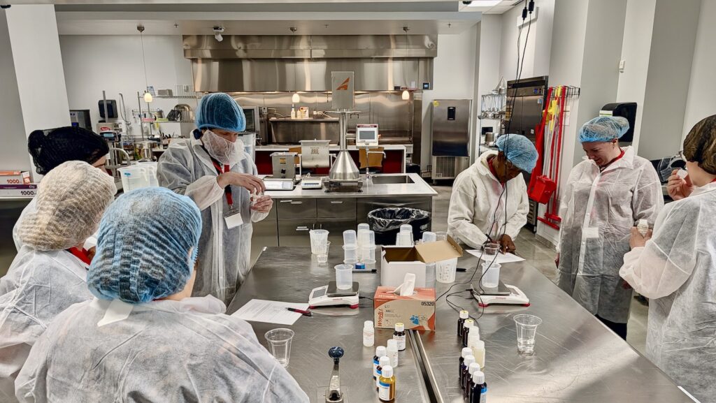 Multiple people in gowns and hair nets working in a food lab at NCFIL. 