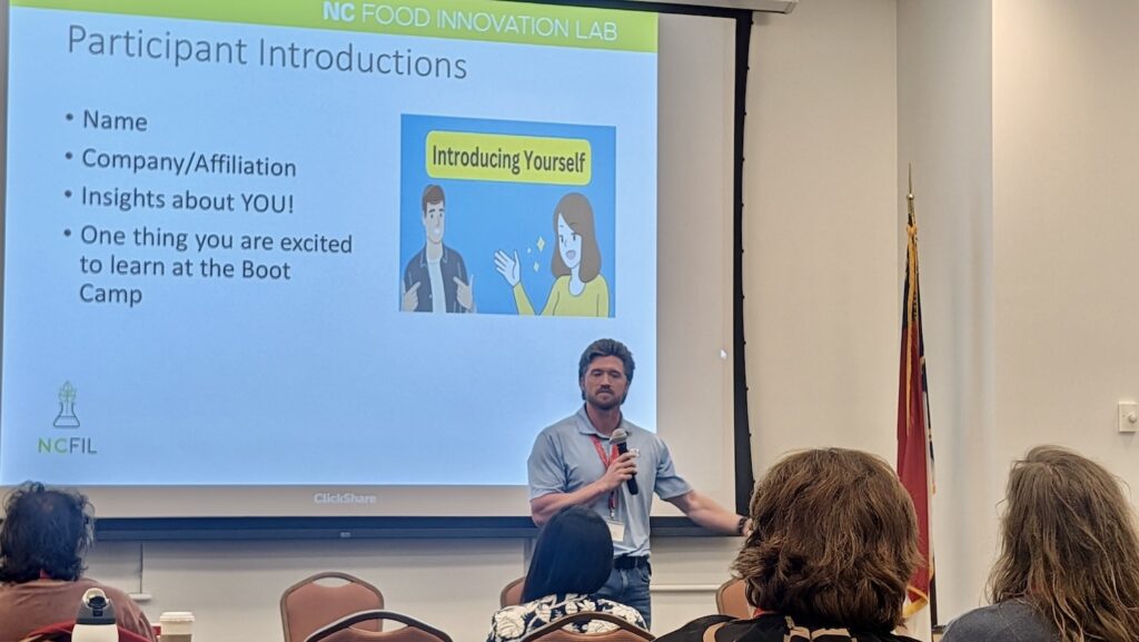 Man speaking in front of a visual presentation at NCFIL Bootcamp. 