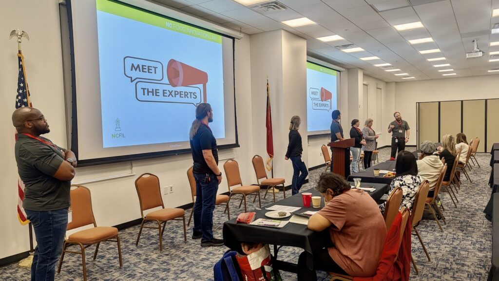 Several presenters in front of visual presentation at NCFIL Bootcamp. 