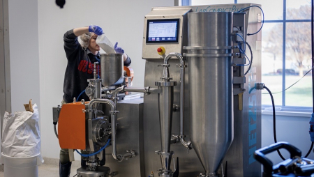 NCFIL staff member loads product into the milling and air classifying equipment